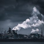 a black and white photo of a factory with smoke stacks