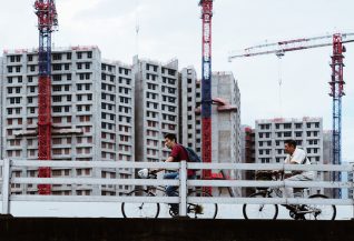 Two men on a bridge with construction site behind