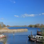 Boats rest peacefully on a calm, blue river.