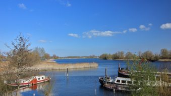 Boats rest peacefully on a calm, blue river.