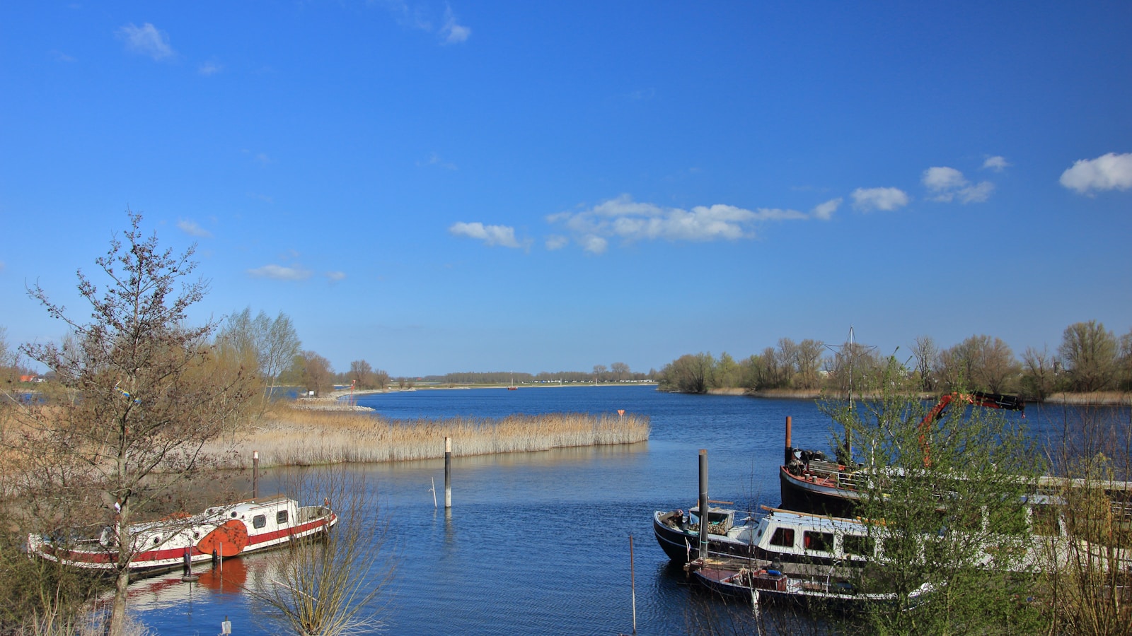 Boats rest peacefully on a calm, blue river.