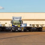 Truck and trailers parked in front of a warehouse.