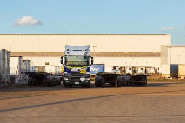 Truck and trailers parked in front of a warehouse.